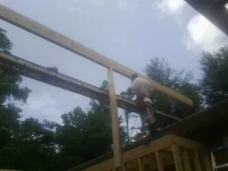 Carpenter setting a ridge beam over a new addition frame — Ice Dam Removal by Roofing Brothers in Mc Grady