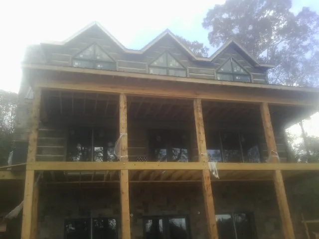 Dormers and porch framing on a large log home under construction — Roof Coating work by our crew in Mc Grady