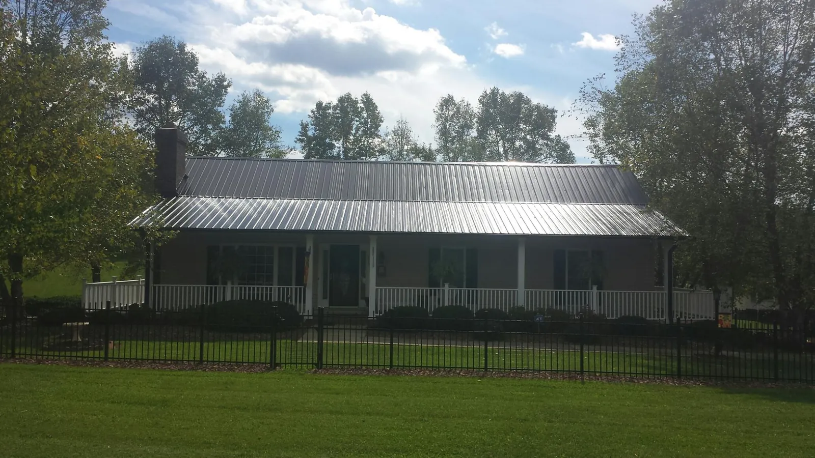 Gray metal roof on a brick ranch with a full width front porch — Gutter Guard Installation work by our crew in Mc Grady