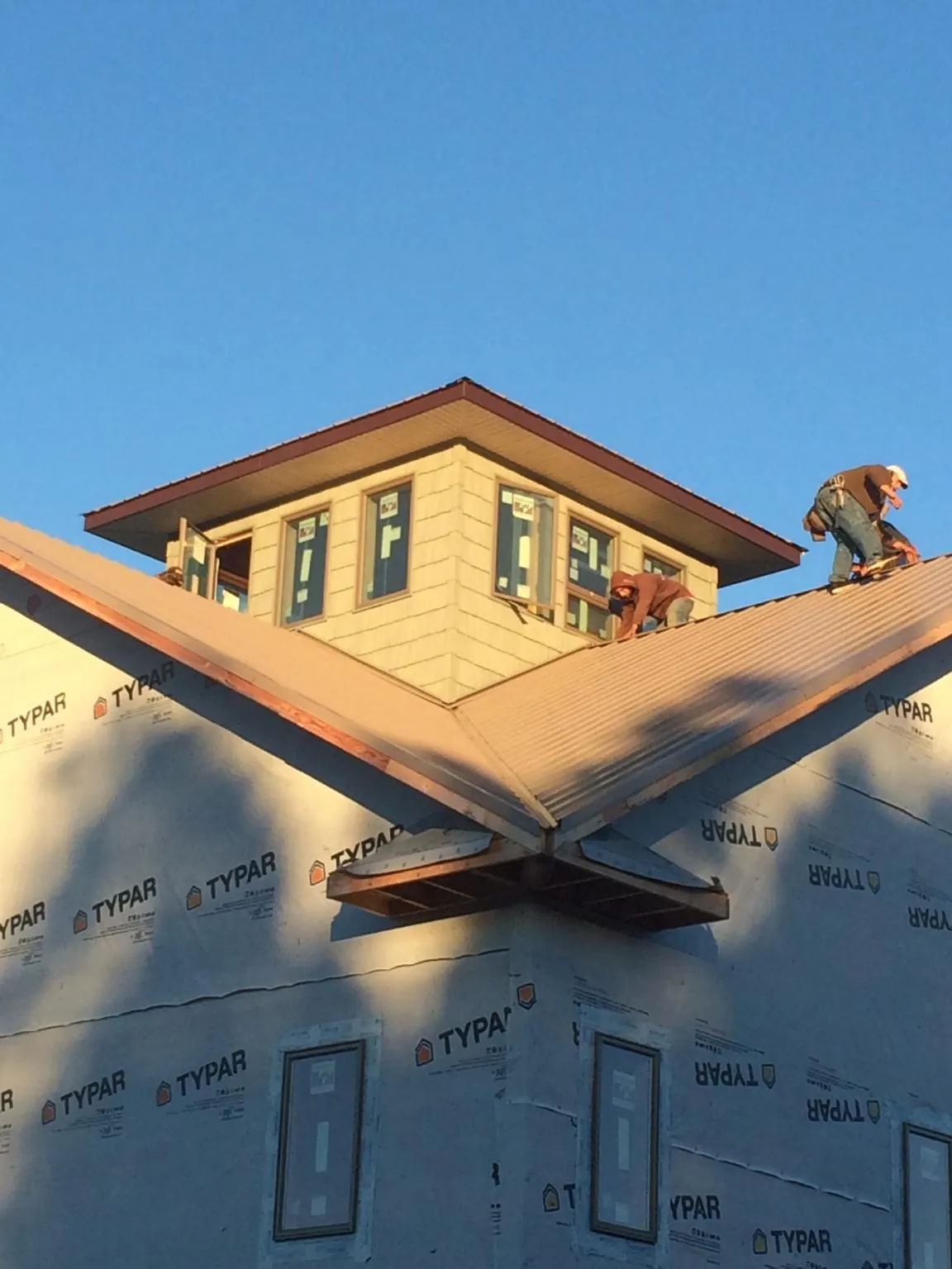 Roofers working around a rooftop cupola on a new metal roof at sunset — Roof Waterproofing in Mc Grady by Roofing Brothers